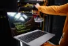 Technician working on server hardware with code displayed on a laptop in a data center.